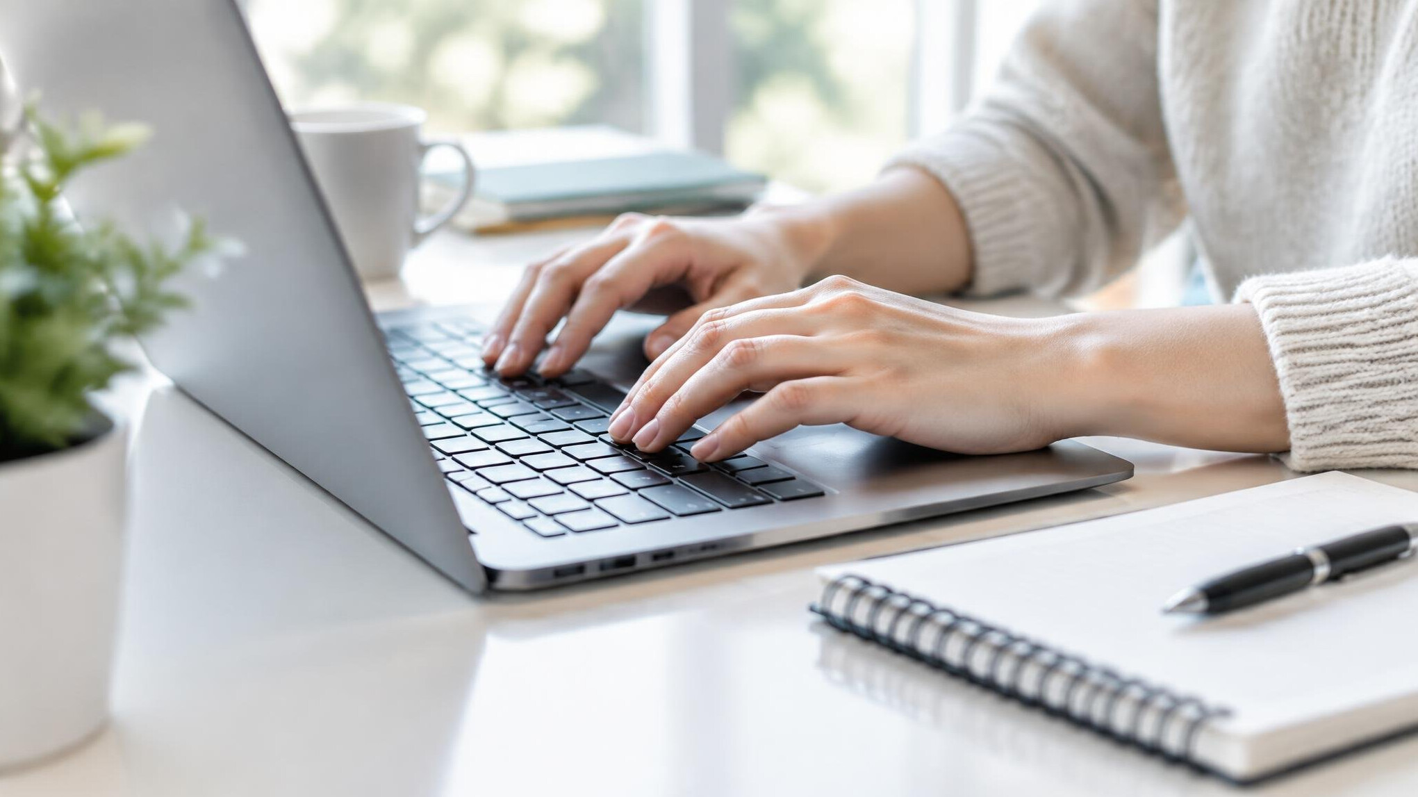 Hands typing on a laptop while planning a monthly budget